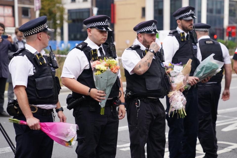 Polizisten legen am Tatort in Croydon Blumen nieder (James Manning/PA Wire)