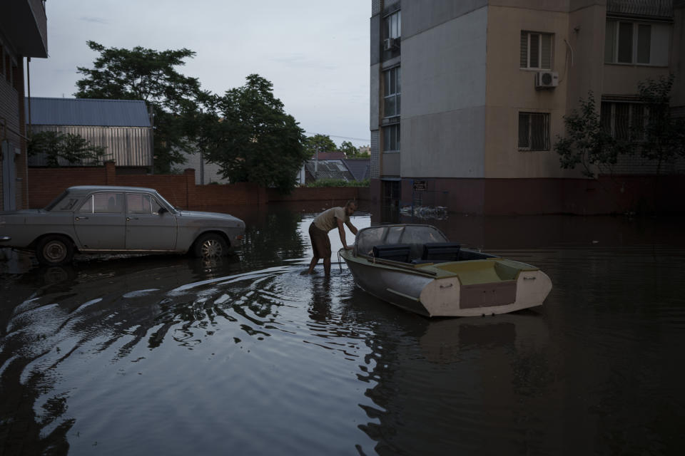 A man pushes a boat in a flooded neighborhood in Kherson, Ukraine, Wednesday, June 7, 2023. Floodwaters from a collapsed dam kept rising in southern Ukraine on Wednesday, forcing hundreds of people to flee their homes in a major emergency operation that brought a dramatic new dimension to the war with Russia, now in its 16th month. (AP Photo/Felipe Dana)