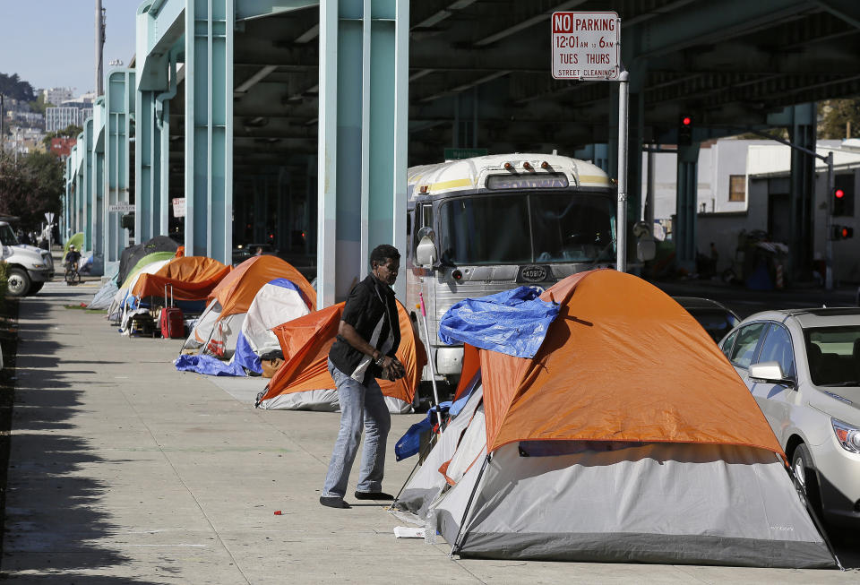 FILE - In this Feb. 23, 2016 file photo, a man stands outside his tent on Division Street in San Francisco. A key federal count shows the number of homeless people increased by double-digit percentages in three San Francisco area counties over two years. In San Francisco, the number of homeless people jumped 17% to more than 8,000 in 2019. Legislators have said repeatedly the state is in the midst of a housing crisis. But the biggest housing bill of the session, which would have overridden local zoning rules in some areas to allow for the construction of more homes, appears to be dead for the year but could be considered next year. (AP Photo/Eric Risberg, File)