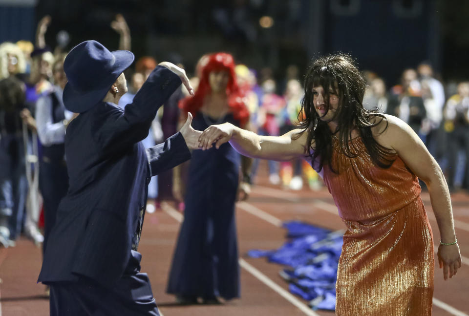 In this photo provided by Fritz Senftleber, people participate in the “drag ball" halftime show at Burlington High School on Friday, Oct. 15, 2021 in Burlington, Vt. The event was part of that school's homecoming and was sponsored by the Gender Sexuality Alliance from Burlington and South Burlington high schools. The football game was between a team made up of students from three Burlington-area schools Burlington, South Burlington and Winooski High Schools who played against St. Johnsbury Academy. (Fritz Senftleber via AP)