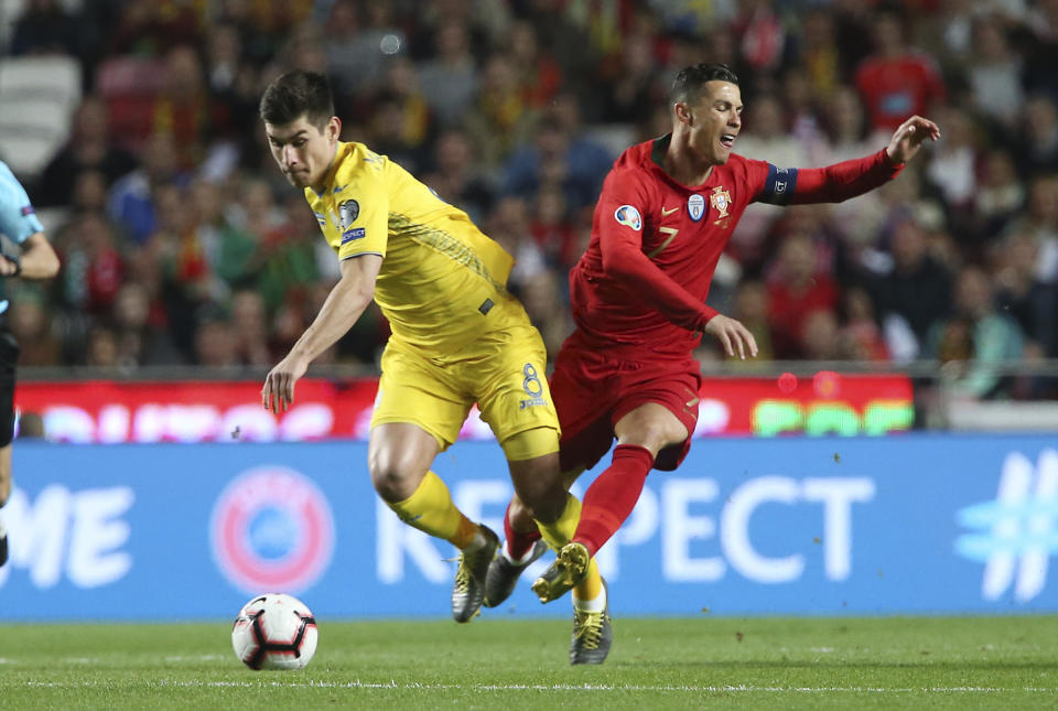 Portugal's Cristiano Ronaldo, right, challenges for the ball with Ukraine's Ruslan Malinovskyi during the Euro 2020 group B qualifying soccer match between Portugal and Ukraine at the Luz stadium in Lisbon, Friday, March 22, 2019. (AP Photo/Armando Franca)