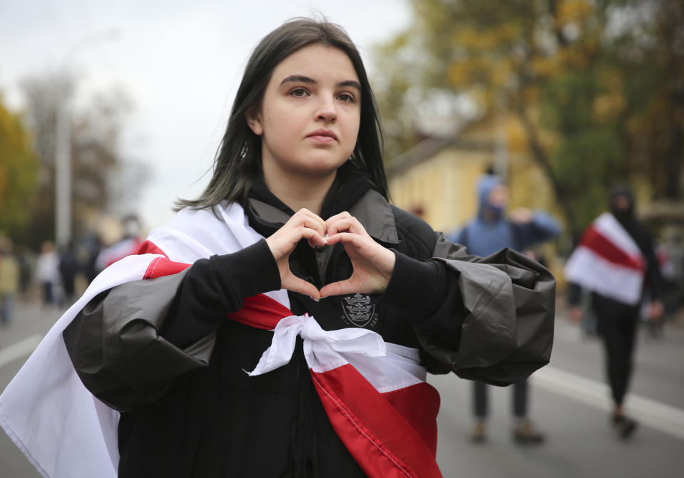 A woman draped in an old Belarusian national flag gestures during an opposition rally to protest the official presidential election results in Minsk, Belarus, Sunday, Oct. 25, 2020. The demonstrations were triggered by official results giving President Alexander Lukashenko 80% of the vote in the Aug. 9 election that the opposition insists was rigged. Lukashenko, who has ruled Belarus with an iron fist since 1994, has accused the United States and its allies of fomenting unrest in the ex-Soviet country. (AP Photo)