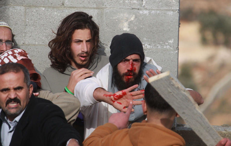 A Palestinian man (L) tries to prevent a fellow Palestinian from the village of Qusra (front) from beating a group of Israeli settlers after they sparked clashes upon entering their village near Nablus, in the Israeli occupied West Bank, on January 7, 2014. (JAAFAR ASHTIYEH/AFP/Getty Images)