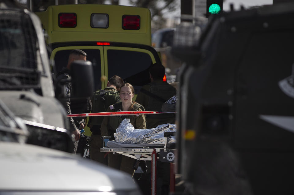 Israeli forces carry a woman's body to an ambulance who was shot and killed at the Qalandia checkpoint between Jerusalem and the West Bank city of Ramallah, Saturday, June 12, 2021. Israeli police say a private security guard at the checkpoint shot and killed the woman who allegedly planned to carry out a stabbing attack. The police said in a statement that the guard saw the woman with a knife and shot her. (AP Photo/Majdi Mohammed)