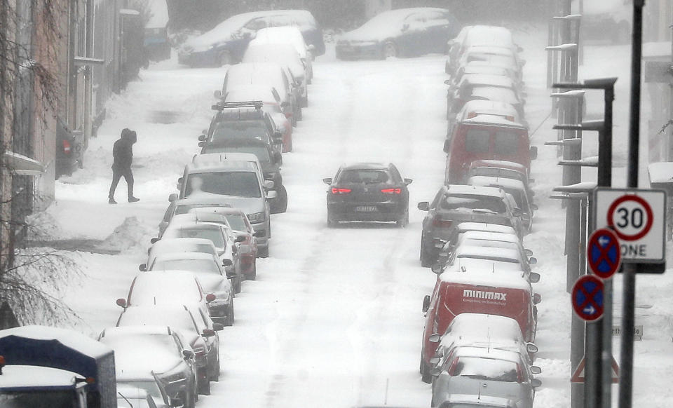 Parking cars are covered with snow during heavy snowfall in Gelsenkirchen, Germany, Sunday, Feb. 7, 2021. Snow falls extremely seldom in the industrial Ruhr area. (AP Photo/Martin Meissner)