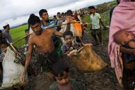 <p>A Rohingya ethnic minority from Myanmar carries a child in a sack and walks through rice fields after crossing over to the Bangladesh side of the border near Cox’s Bazar’s Teknaf area, Friday, Sept. 1, 2017. (Photo: Bernat Armangue/AP) </p>