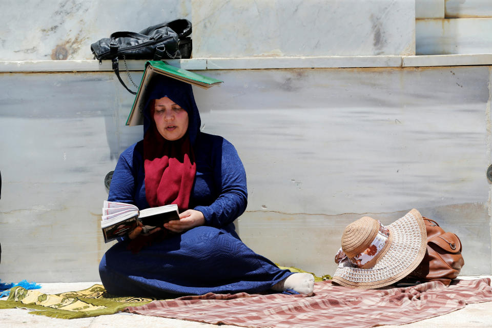 A Muslim woman protects herself from the sun as she prays during the Friday prayers for Ramadan, on the compound known to Muslims as Noble Sanctuary and to Jews as Temple Mount in Jerusalem's Old City June 16, 2017 . REUTERS/Ammar Awad