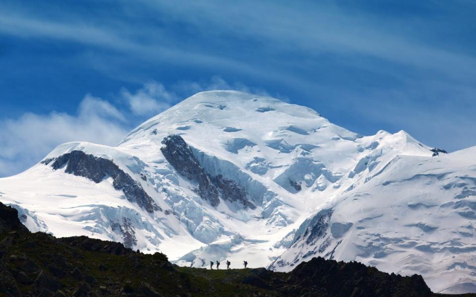 Hikers on a ridge with Mt Blanc in the background - Getty