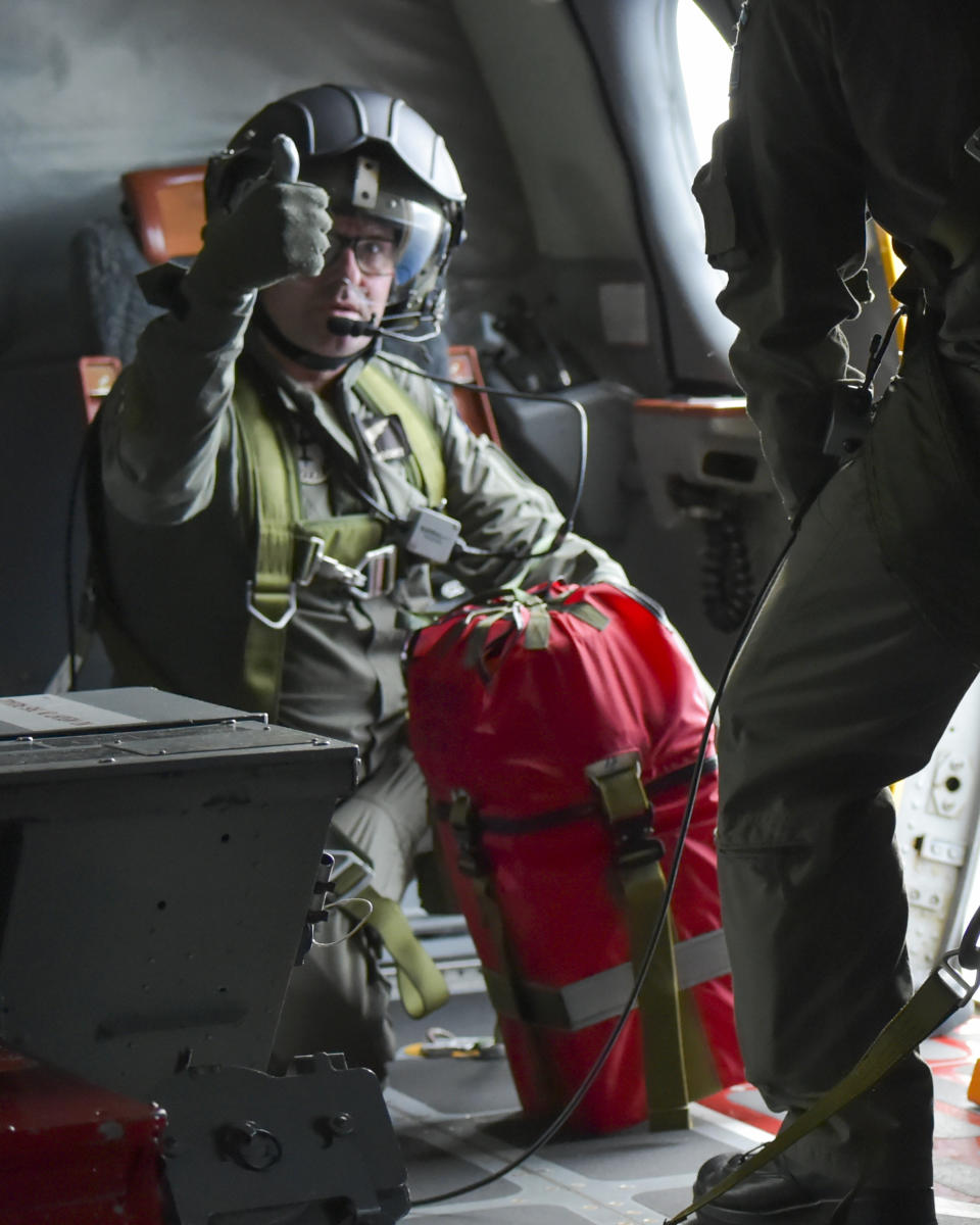 In this image supplied by the Royal New Zealand Air Force (RNZAF), a crew member of a RNZAF Orion gestures before dropping a survival pack to a boat near Makin Island in Kiribati, Monday, May 23, 2022. New Zealand's military said Tuesday that an air force plane found seven people who had gone missing. They were aboard two small boats near the remote Pacific nation of Kiribati. (RNZAF via AP)