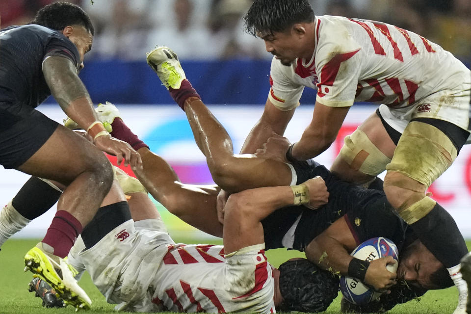 England's Joe Marchant, right is brought down by Japan's Pieter Labuschagne during the Rugby World Cup Pool D match between England and Japan in the Stade de Nice, in Nice, France Sunday, Sept. 17, 2023. (AP Photo/Pavel Golovkin)