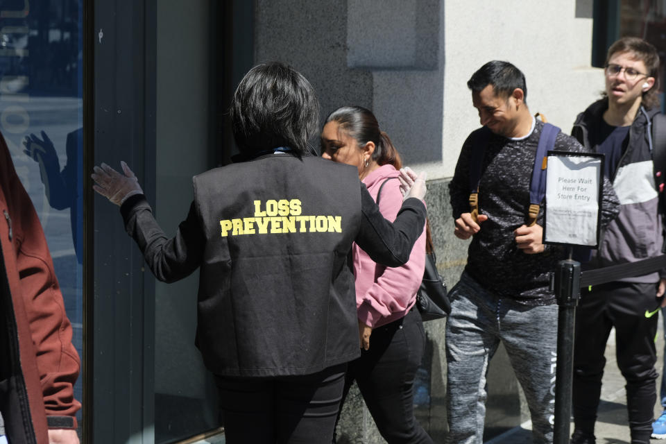 Shoppers wait in line outside a Ross discount store as a loss prevention specialist lets them in a few at a time in San Francisco, on June 21, 2023. San Francisco's downtown has seen an exodus of retailers. While San Francisco faces some of its own unique issues the problems serve as warning signs for other downtowns across the country, which are also feeling some pain. (AP Photo/Eric Risberg)