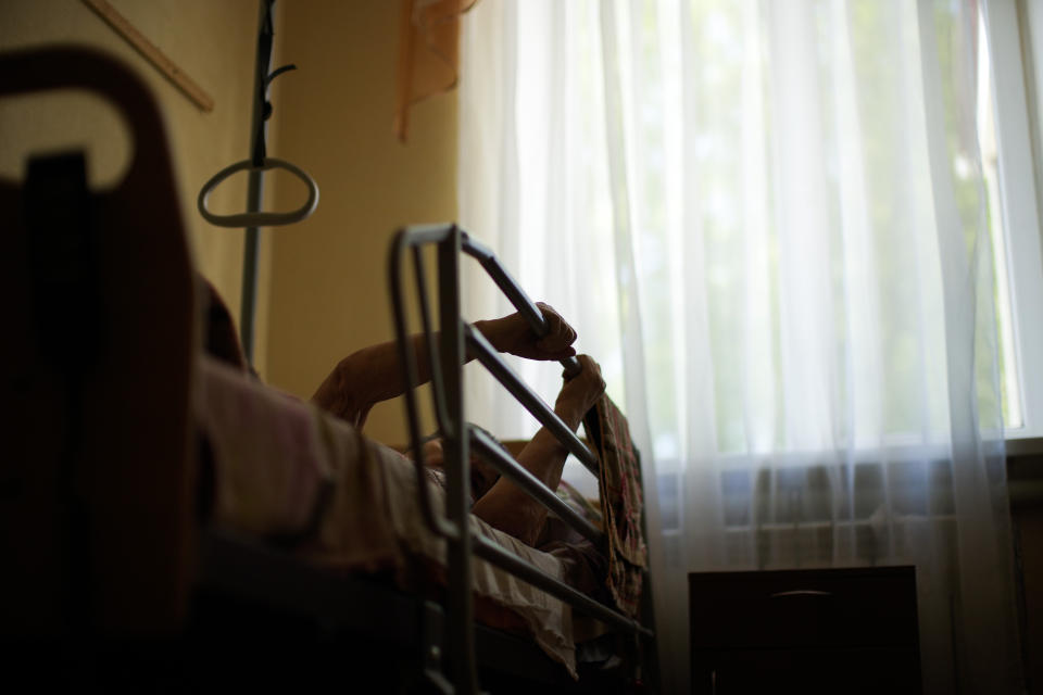 An elderly resident lays in her bed in a facility for people with mental and physical disabilities, in her bedroom in the village of Tavriiske, Ukraine, Wednesday, May 11, 2022. With around 425 residents, the institution is the largest such facility for people with disabilities in southeastern Ukraine's Zaporizhzhia region. (AP Photo/Francisco Seco)