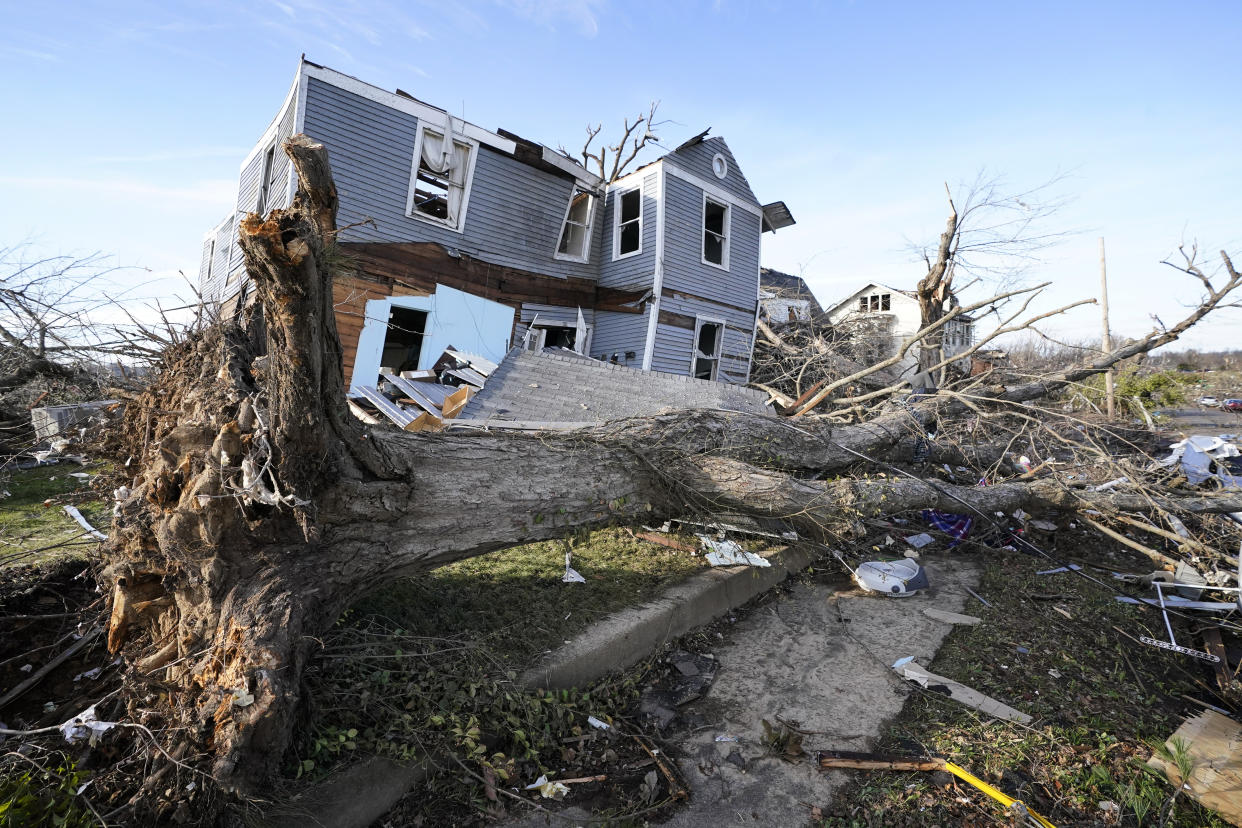 FILE -An overturned tree sits in front of a tornado damaged home in Mayfield, Ky., on Saturday, Dec. 11, 2021. Tornadoes and severe weather caused catastrophic damage across multiple states killing dozens of people overnight. The holiday season tragedy killed 81 people in Kentucky and turned buildings intomounds ofrubble as damage reached into hundreds of millions of dollars.(AP Photo/Mark Humphrey, File)