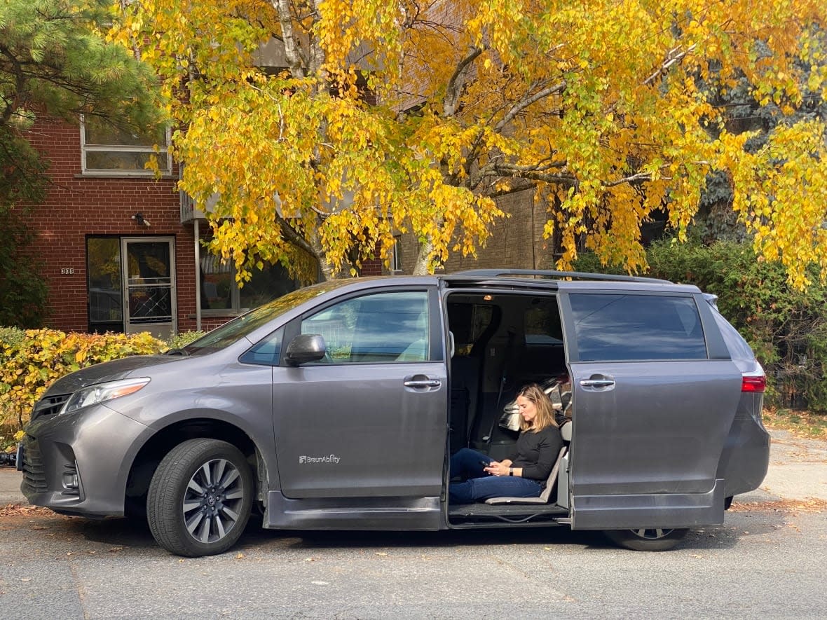 Michelle Cousins makes herself comfortable with a pillow and a blanket in her accessible van while she camps out near her daughter's school in case she needs her help.  (Talia Ricci/CBC - image credit)