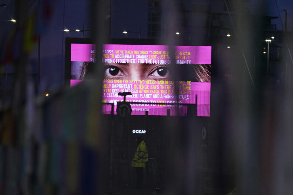 Part of an advertisement can be seen through the fence near the venue for the COP26 U.N. Climate Summit in Glasgow, Scotland, Thursday, Nov. 11, 2021. (AP Photo/Alastair Grant)