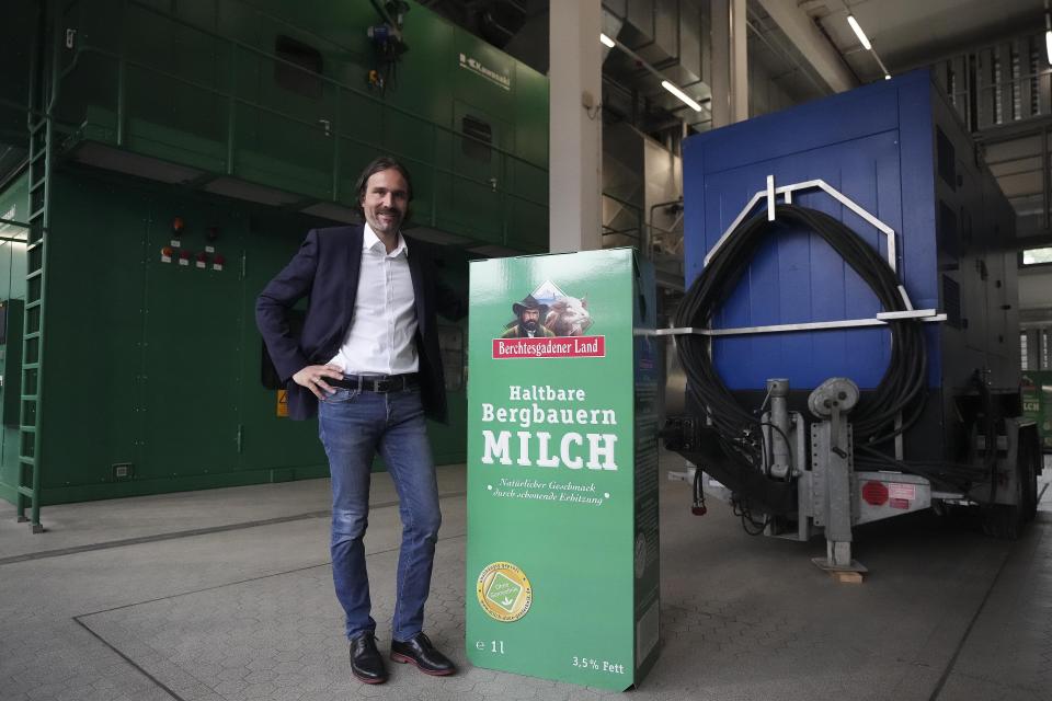 Dairy cooperative managing director Bernhard Pointner poses at an advertising carrier in front of a turbine generator in Piding near Munich, Germany, Friday, July 15, 2022. The Molkerei Berchtesgadener Land has stockpiled 200,000 liters of fuel oil so it can continue to produce electricity and steam if natural gas supplies to its turbine generator are cut off. (AP Photo/Matthias Schrader)