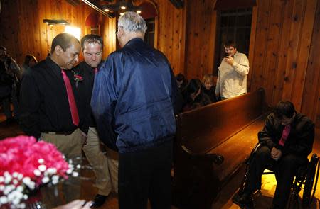 Darren Black Bear (L) and Jason Pickel (C) pray as they are married by Darren's father Rev. Floyd Black Bear (R) in El Reno, Oklahoma October 31, 2013. At a small, turn-of-the-century chapel at Fort Reno, an historic frontier fort 40 miles west of Oklahoma City, a same-sex couple exchanged marriage vows in a state where gay marriage is banned. REUTERS/Rick Wilking