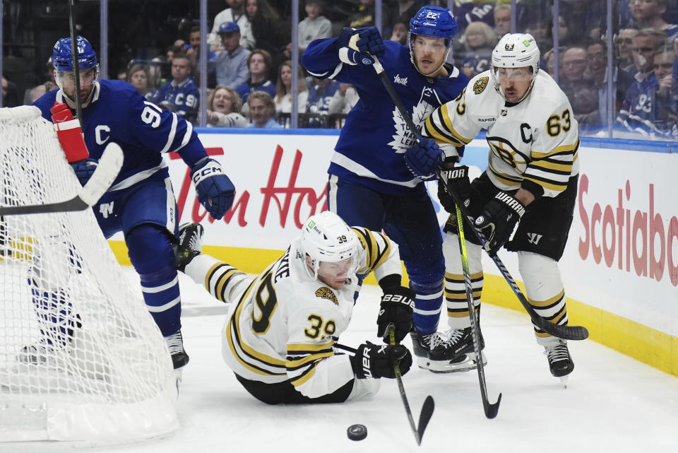 Boston Bruins' Morgan Geekie (39) falls as he battles for the puck with Toronto Maple Leafs' John Tavares (91) as Maple Leafs' Jake McCabe (22) and Bruins' Brad Marchand (63) look on during the third period in Game 6 of an NHL hockey Stanley Cup first-round playoff series in Toronto on Thursday, May 2, 2024. (Nathan Denette/The Canadian Press via AP)