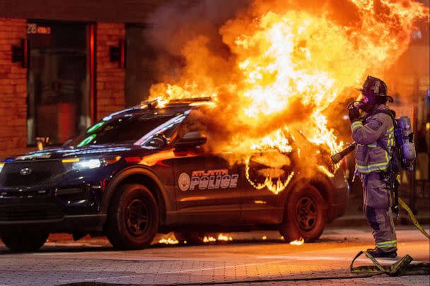 PHOTO: Atlanta firefighters prepared to extinguish a police car that was set afire during a Forest Defenders protest in Atlanta, on Jan 21, 2023. (Steve Schaefer/The Atlanta Journal-Constitution via ZUMA Press)