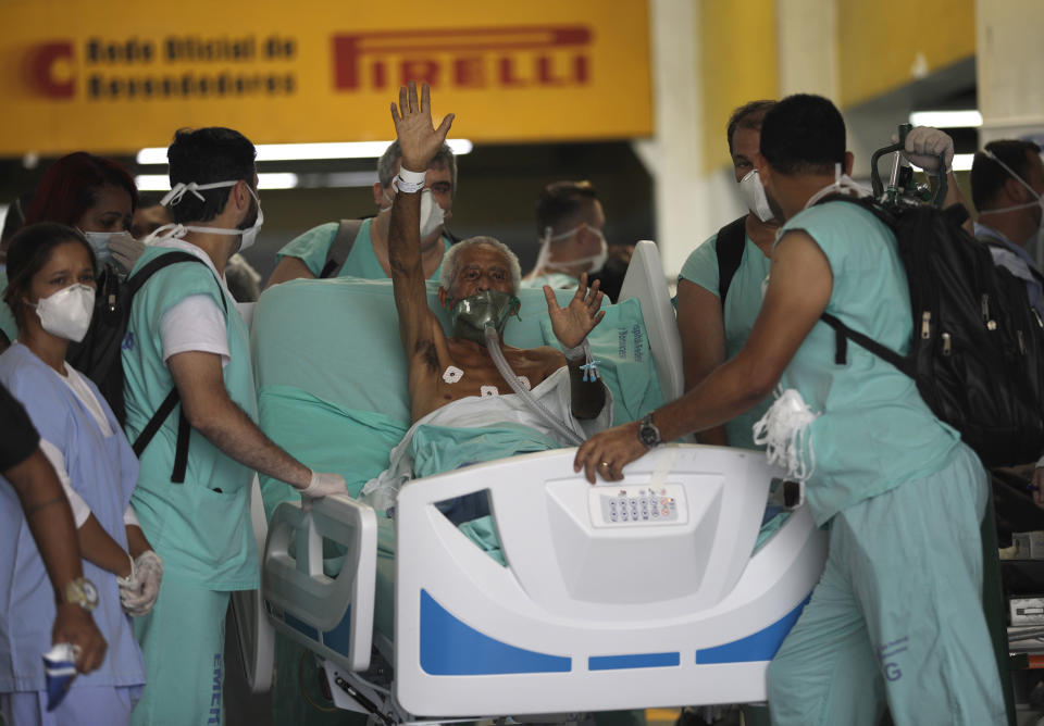A patient waves as he is successfully evacuated from the Bonsucesso Federal Hospital while firefighters douse a blaze in Rio de Janeiro, Brazil, Tuesday, Oct. 27, 2020. According to the hospital, a 42-year-old female COVID-19 patient, who was in critical condition, died while she was being evacuated. (AP Photo/Silvia Izquierdo)