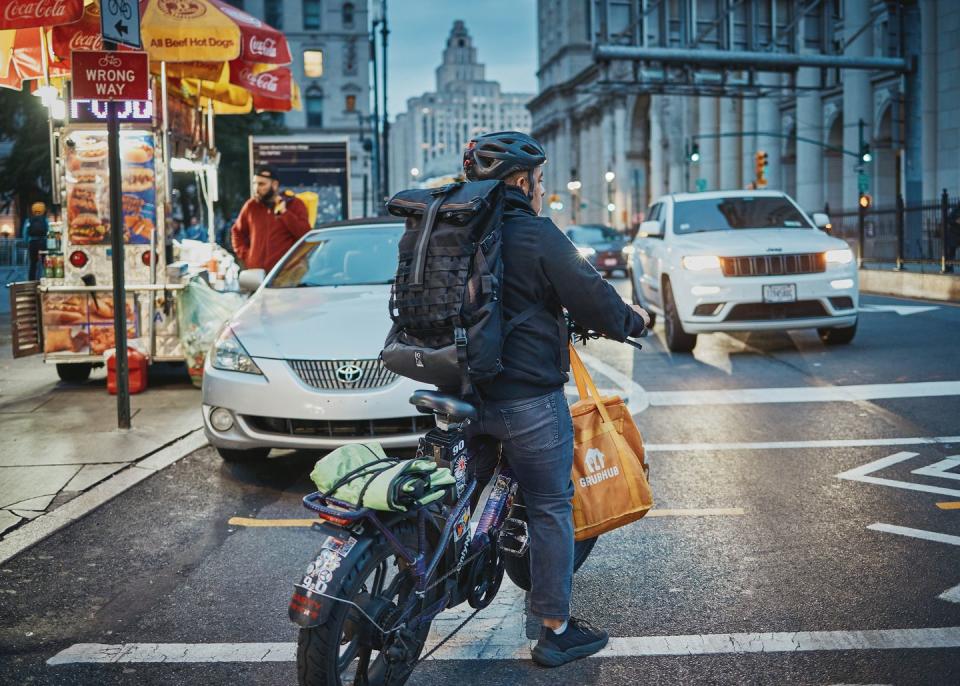 a person on a ebike carrying a bag on a busy street