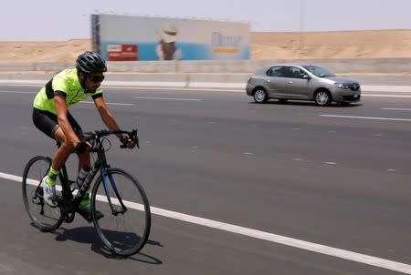 Egyptian cyclist Helmy El Saeed, 27, passes beside a car during training on the highway of El Ain El Sokhna, east of Cairo, Egypt July 19, 2017, as he prepares to break a Guinness record by fastest crossing of Europe. Picture taken July 19, 2017. REUTERS/Amr Abdallah Dalsh