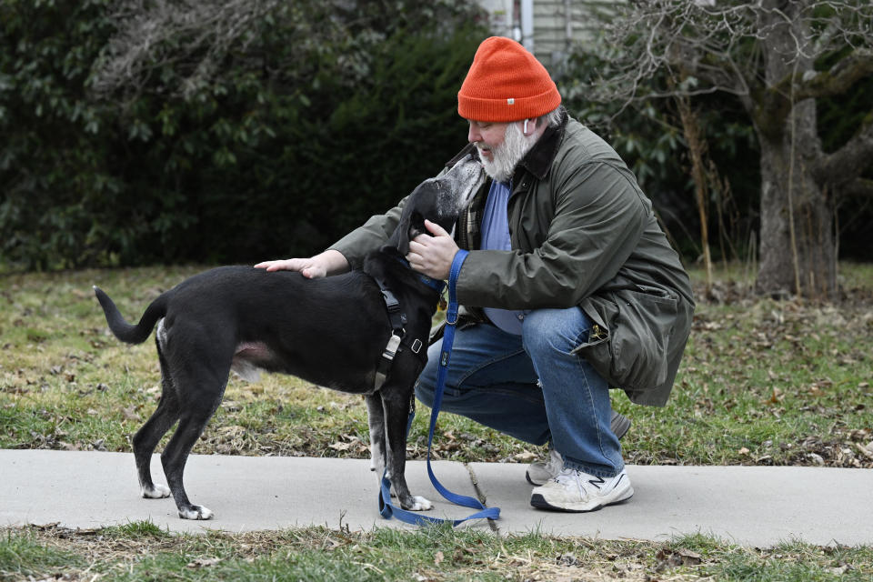 Casey Rosseau wears earbuds to listen to an e-book when he walks his dog Darcy in West Hartford, Conn., Feb. 1, 2024. Rosseau, who estimates he reads about 200 books a year, said he'd like to see more regulation of what publishers can charge libraries. Libraries have been grappling with soaring costs of digital titles, both e-books and audio books, that libraries typically lease from publishers for a year or two, with limited usage. (AP Photo/Jessica Hill)