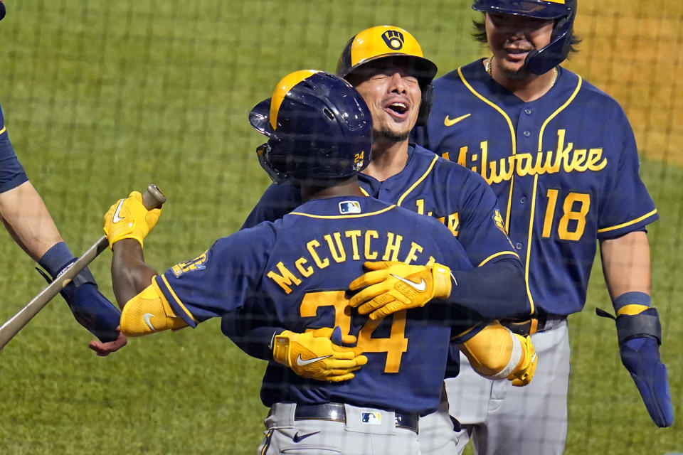 Milwaukee Brewers' Willy Adames, center right, celebrates with Andrew McCutchen (24) as he returns to the dugout after hitting a grand slam off Pittsburgh Pirates relief pitcher Cam Vieaux during the eighth inning of a baseball game in Pittsburgh, Friday, July 1, 2022. (AP Photo/Gene J. Puskar)