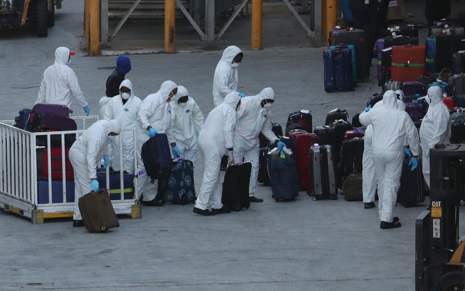 Workers dressed in hazmat suits take the luggage of Zaandam - Getty