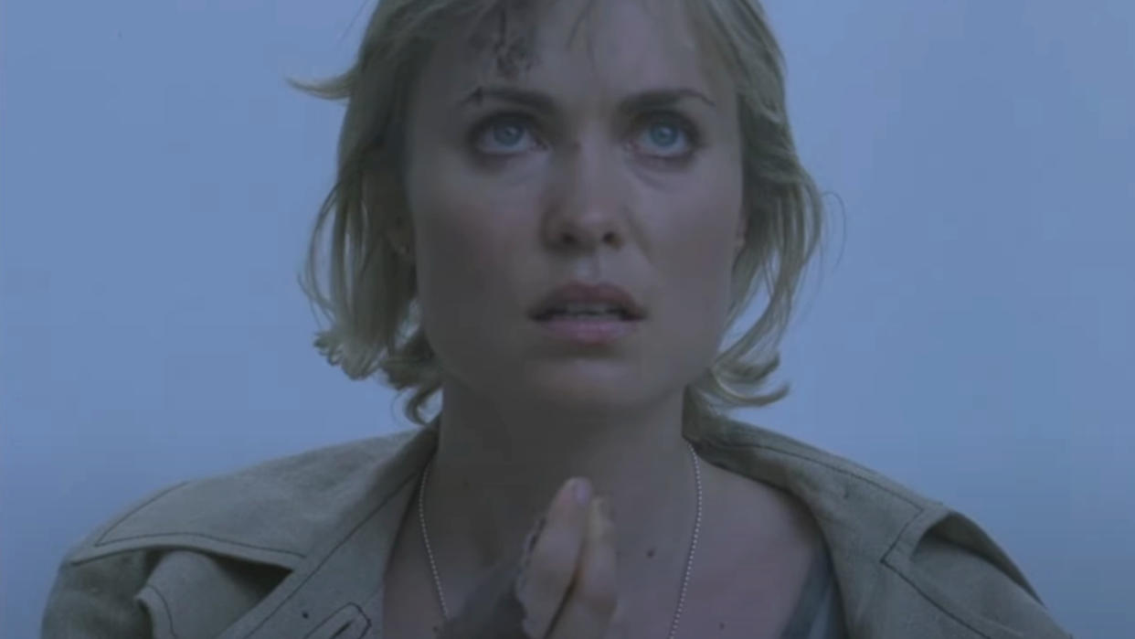  Radha Mitchell looks up in confusion while standing in a grey fog in Silent Hill. 