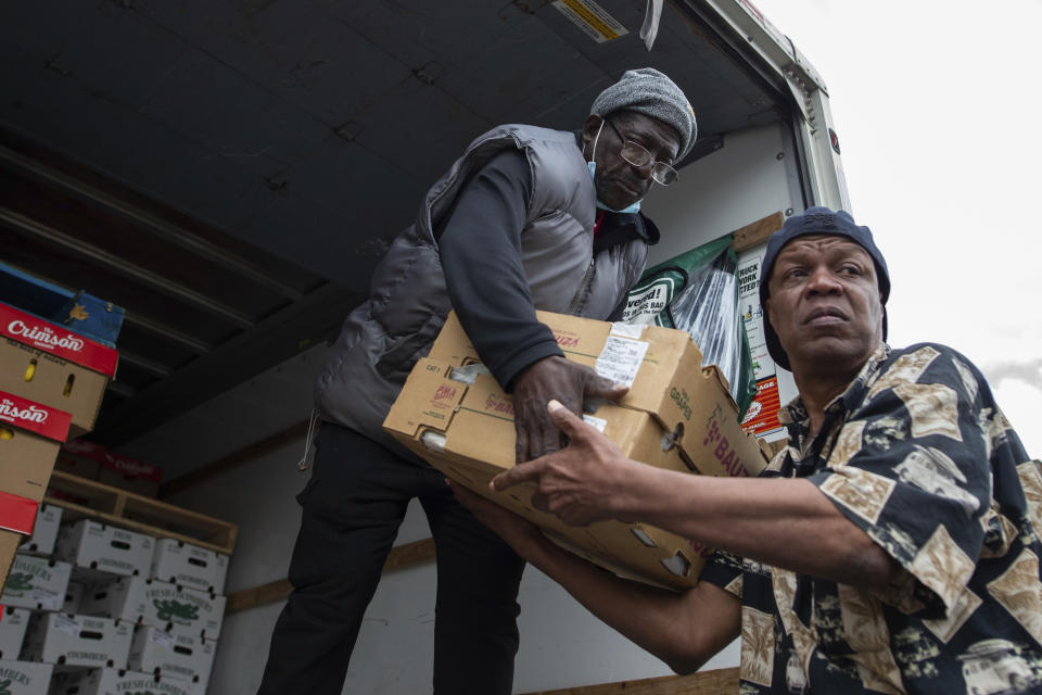 Timothy Boarman, left, and Swanson Owens unload a truck of fresh produce to be given out to people affected by the Tops Friendly Market closure, Tuesday, May 17, 2022, in Buffalo, N.Y. (AP Photo/Joshua Bessex)