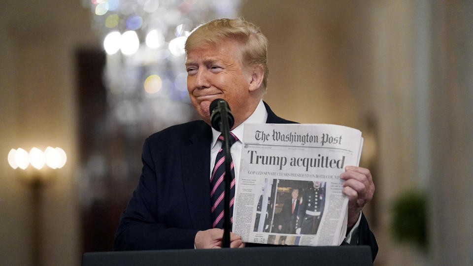 President Trump holds a copy of the Washington Post in the East Room on Feb. 6. (Evan Vucci/AP)