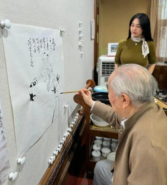 中國書畫大師范曾上傳新婚妻子徐萌一旁看他作畫的照片。翻攝百度