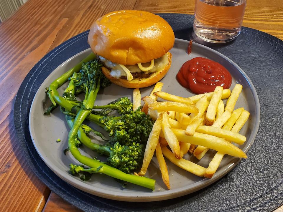 plate with burger, broccolini, french fries, and ketchup