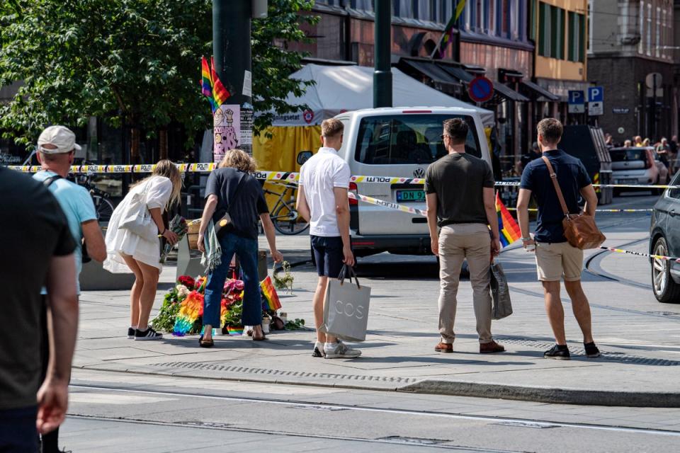 People lay rainbow flags along the street near a restaurant with windows shattered by the shooting (Getty)