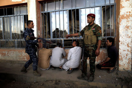 Iraqi army soldiers keep guard over suspected Islamic State militants at a processing center for displaced people in Qayyara, south of Mosul. REUTERS/Zohra Bensemra