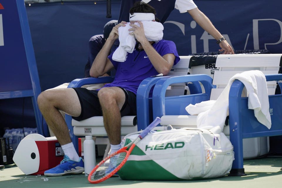 Taylor Fritz, of the United States, wraps his head is ice-cold towels between sets during a match against Daniel Evans, of Britain, at the Citi Open tennis tournament in Washington, Thursday, Aug. 4, 2022. (AP Photo/Carolyn Kaster)