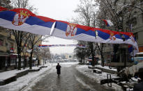 Workers hang Serbian flags in the northern, Serb-dominated part of ethnically divided town of Mitrovica, Kosovo, Friday, Dec. 14, 2018. Kosovo's parliament overwhelmingly approved the formation of an army, a move that has angered Serbia which says it would threaten peace in the war-scarred region. (AP Photo/Darko Vojinovic)