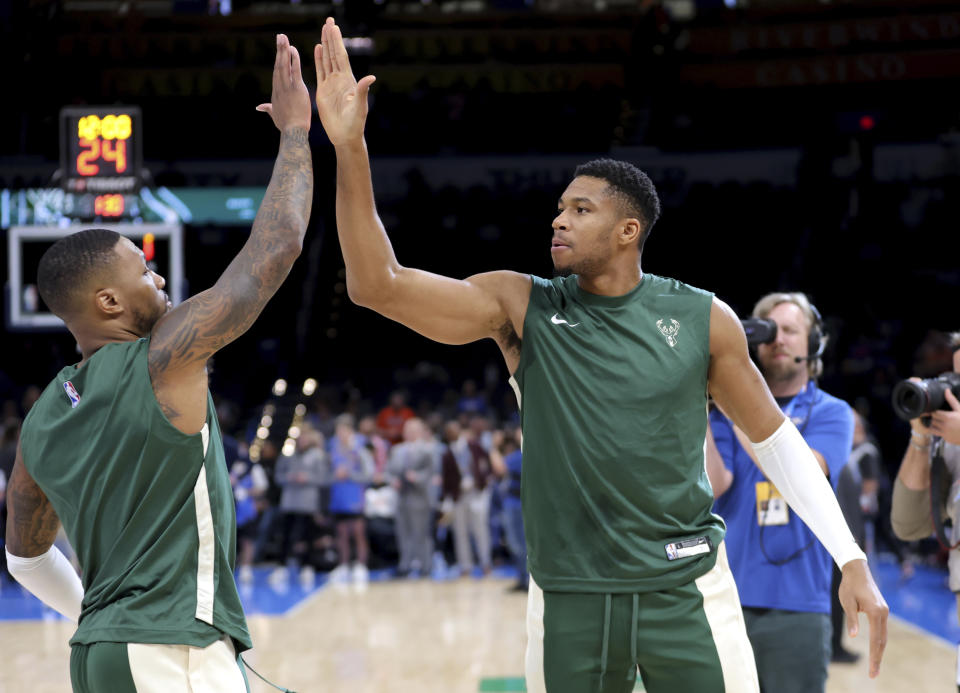 Milwaukee Bucks forward Giannis Antetokounmpo, right, high fives Milwaukee Bucks guard Damian Lillard (0) before the start of a preseason NBA basketball game against the Oklahoma City Thunder, Tuesday, Oct. 17, 2023, in Oklahoma City. (AP Photo/Sarah Phipps)