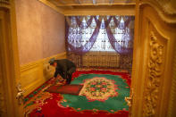 Tursunjan Mamat sets down a copy of the Quran during a government organized visit for foreign journalists to his home in Aksu in western China's Xinjiang Uyghur Autonomous Region on April 20, 2021. Under the weight of official policies, the future of Islam appears precarious in Xinjiang, a remote region facing Central Asia in China's northwest corner. Outside observers say scores of mosques have been demolished, which Beijing denies, and locals say the number of worshippers is on the decline. (AP Photo/Mark Schiefelbein)