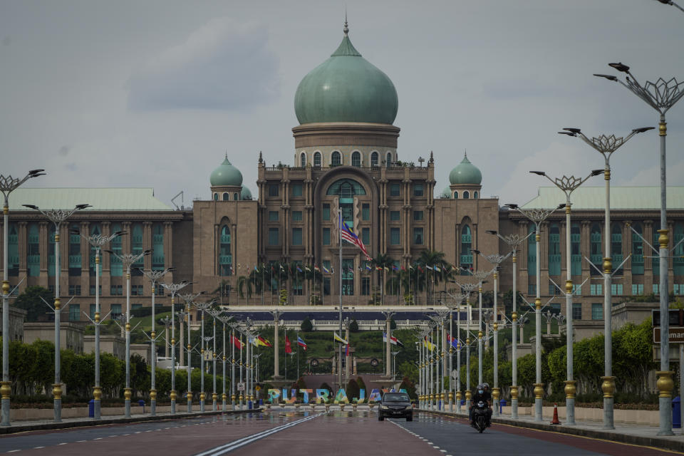 Motorists drive in front of the prime minister's office building in Putrajaya, Malaysia, Friday, Oct. 23, 2020. Malaysian opposition leader Anwar Ibrahim said Friday he was concerned about reports that Prime Minister Muhyiddin Yassi may invoke emergency laws to suspend Parliament and stymie bids to oust his government. (AP Photo/Vincent Thian)