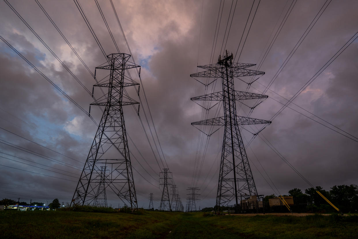 A row of transmission towers stretches into the distance against a stormy sky.