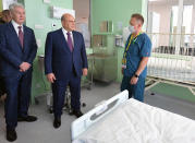 FILE - In this Friday, June 18, 2021, file photo, Russian Prime Minister Mikhail Mishustin, center, and Moscow's Mayor Sergei Sobyanin, left, visit the hospital for coronavirus patients in Kommunarka, outside Moscow, Russia. An ambitious plan of vaccinating 30 million Russians by mid-June against the coronavirus has fallen short by a third, and the country has started to see a surge in daily new infections. So now, many regional governments across the vast country are obligating some workers to get vaccinated and requiring the shots to enter certain businesses, like restaurants. (Alexander Astafyev, Sputnik/Kremlin Pool Photo via AP, File)