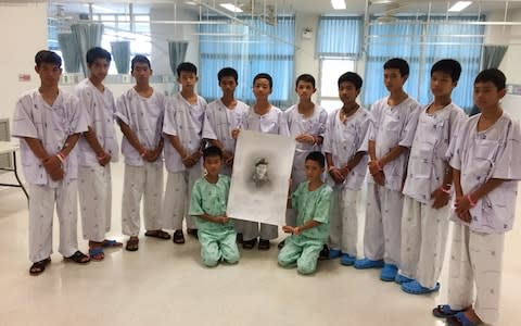 The boys are seen in hospital clothes posing with a drawing of the Navy SEAL diver who died during the rescue mission - Credit: Chiang Rai Prachanukroh Hospital and Ministry of Health/AFP