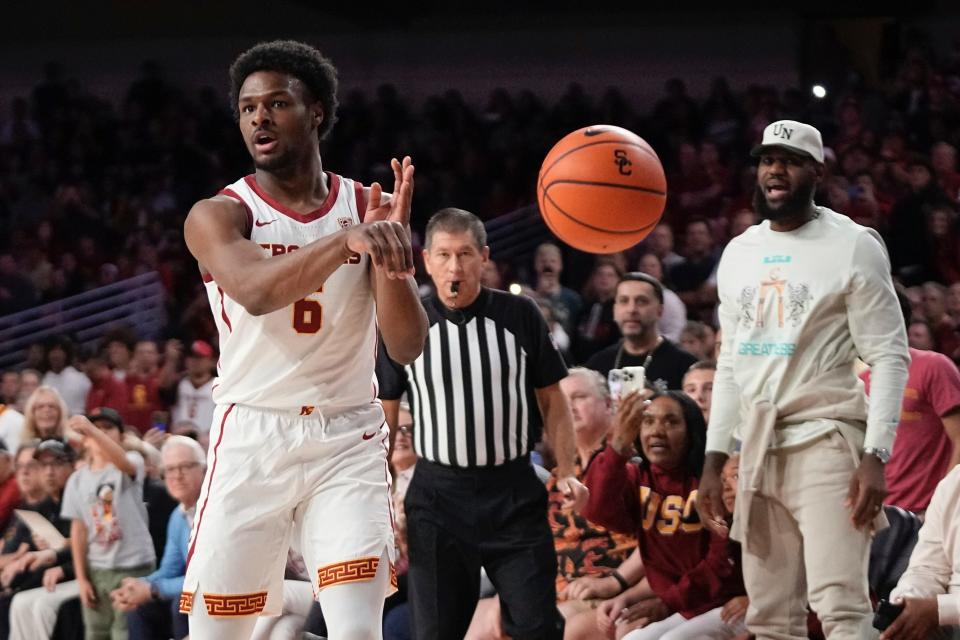 Southern California guard Bronny James, left, passes the ball as his father LeBron James, right, watches during the first half of an NCAA college basketball game against Long Beach State Sunday, Dec. 10, 2023, in Los Angeles. (AP Photo/Mark J. Terrill)