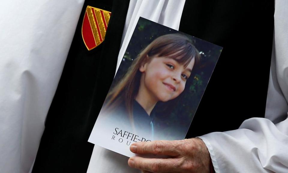 A member of the clergy holds a picture of Saffie