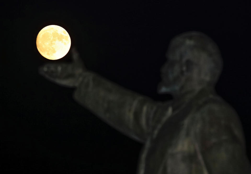 A full moon rises behind a statue of Soviet state founder Vladimir Leni