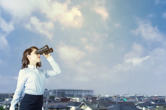 Woman with binoculars looking off into the distance.