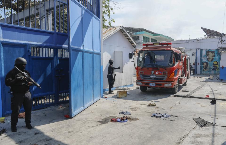 Firefighters arrive to put out a small fire at the empty National Penitentiary as National Police patrol in downtown Port-au-Prince, Haiti, Haiti, Thursday, March 14, 2024. This is the same facility that armed gangs stormed late March 2 and hundreds of inmates escaped. (AP Photo/Odelyn Joseph)