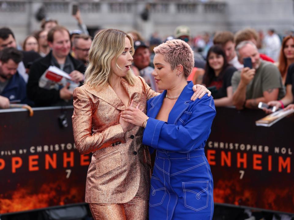 Emily Blunt and Florence Pugh hold Blunt's blazer closed to prevent a wardrobe malfunction.